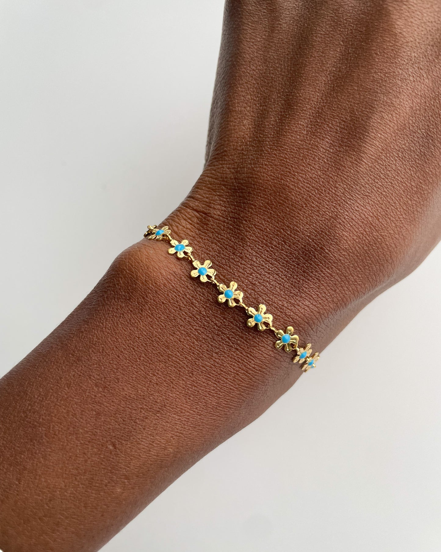 Gold bracelet with blue stones on a wrist against a white background