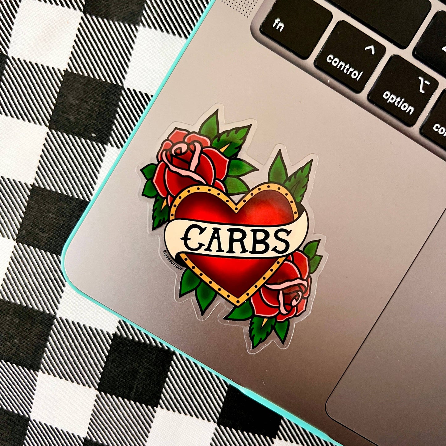 Heart-shaped tattoo design with roses and 'CARBS' text on a laptop