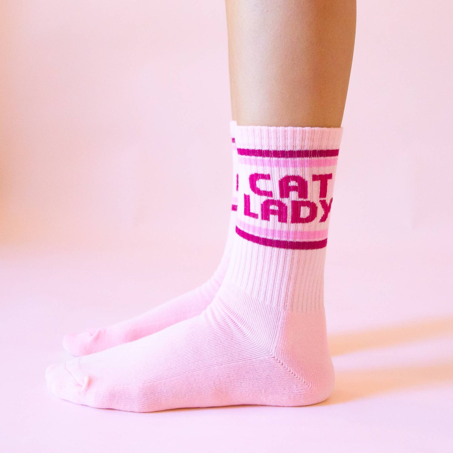 White socks with pink text worn by a person on a pink background