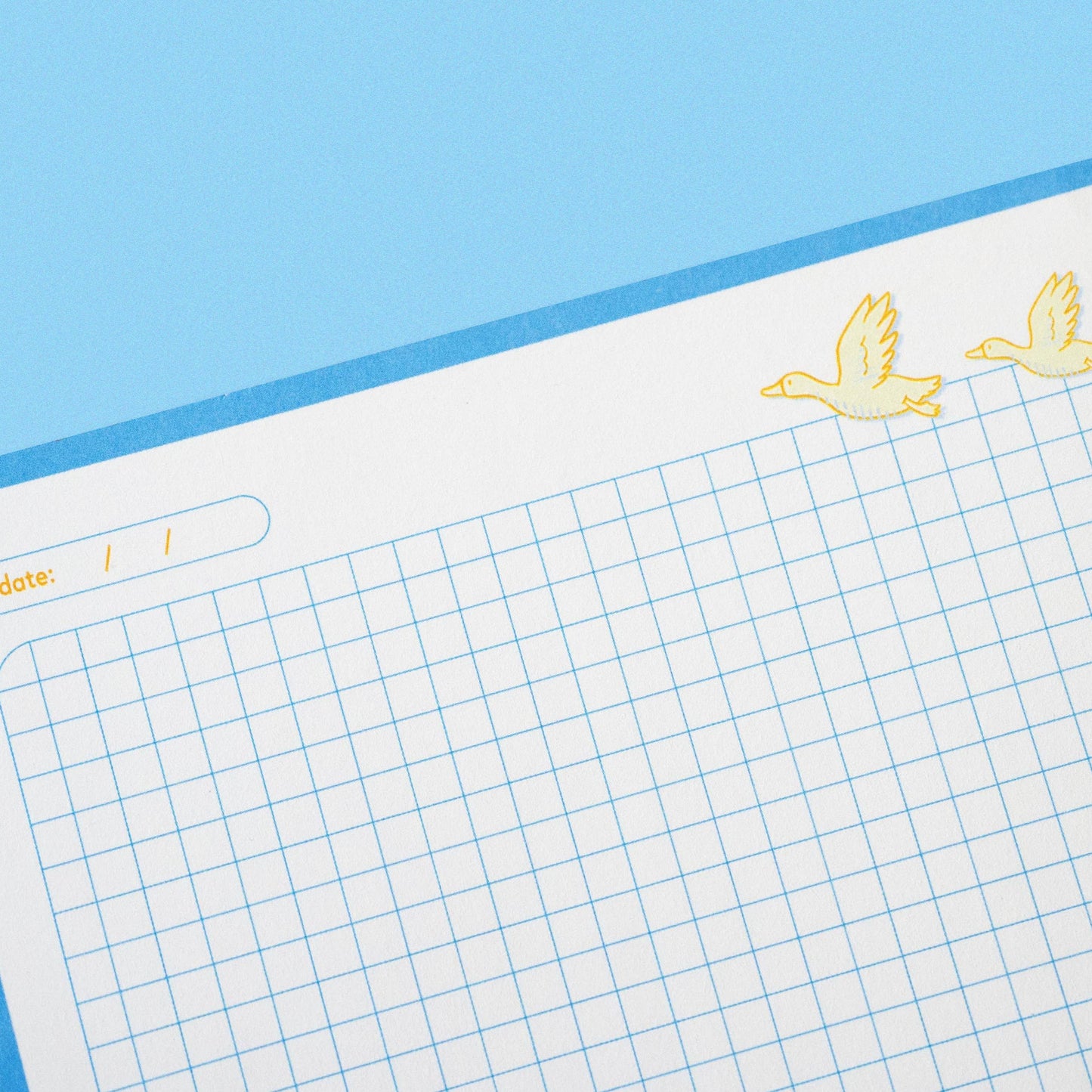 Grid paper with decorative corner stickers on a blue background
