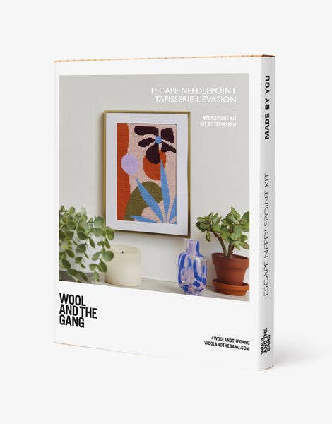 Wool and the Gang needlepoint kit packaging with a framed artwork on a shelf.