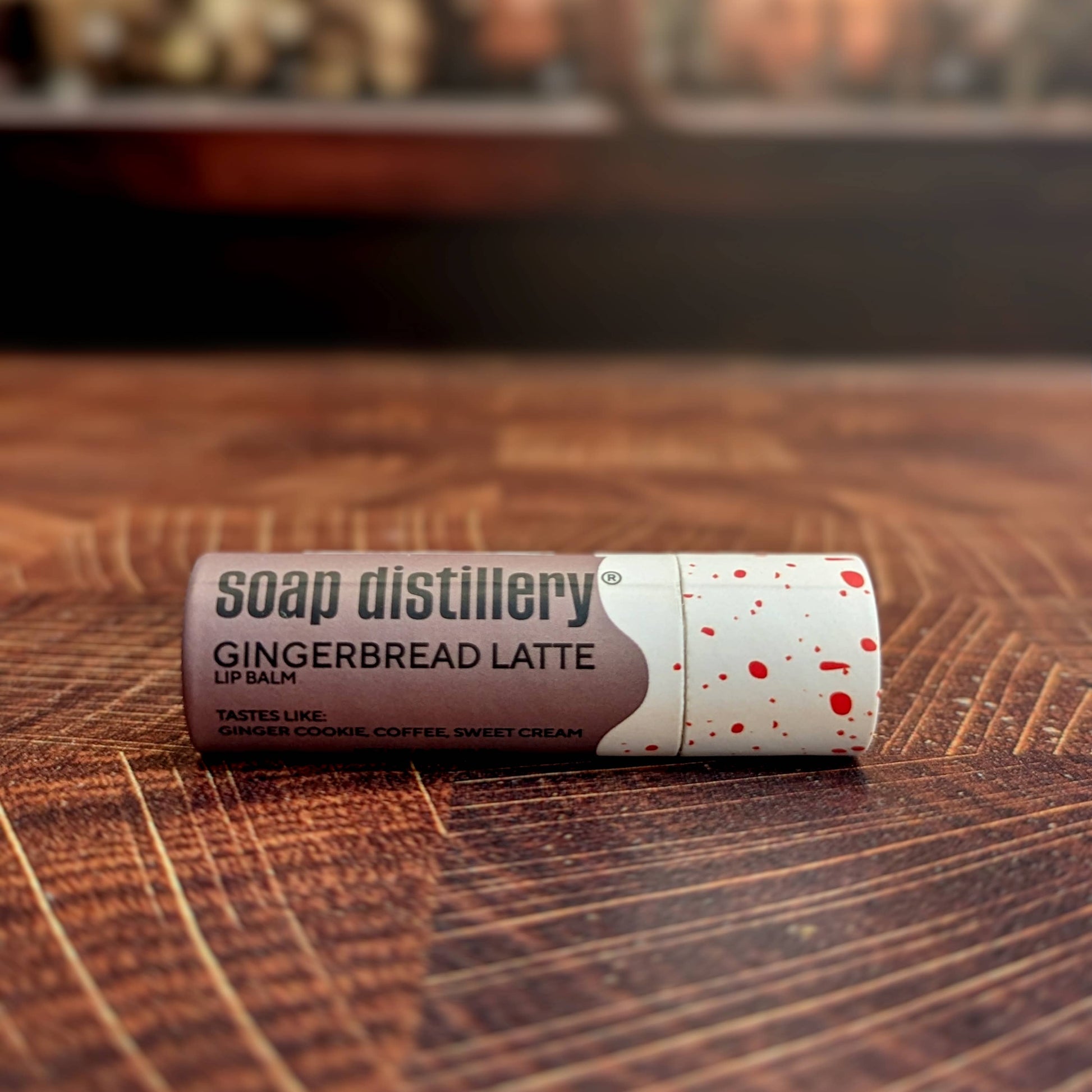 Lip balm with 'Soap Distillery' branding on a wooden surface, Gingerbread Latte Lip Balm
