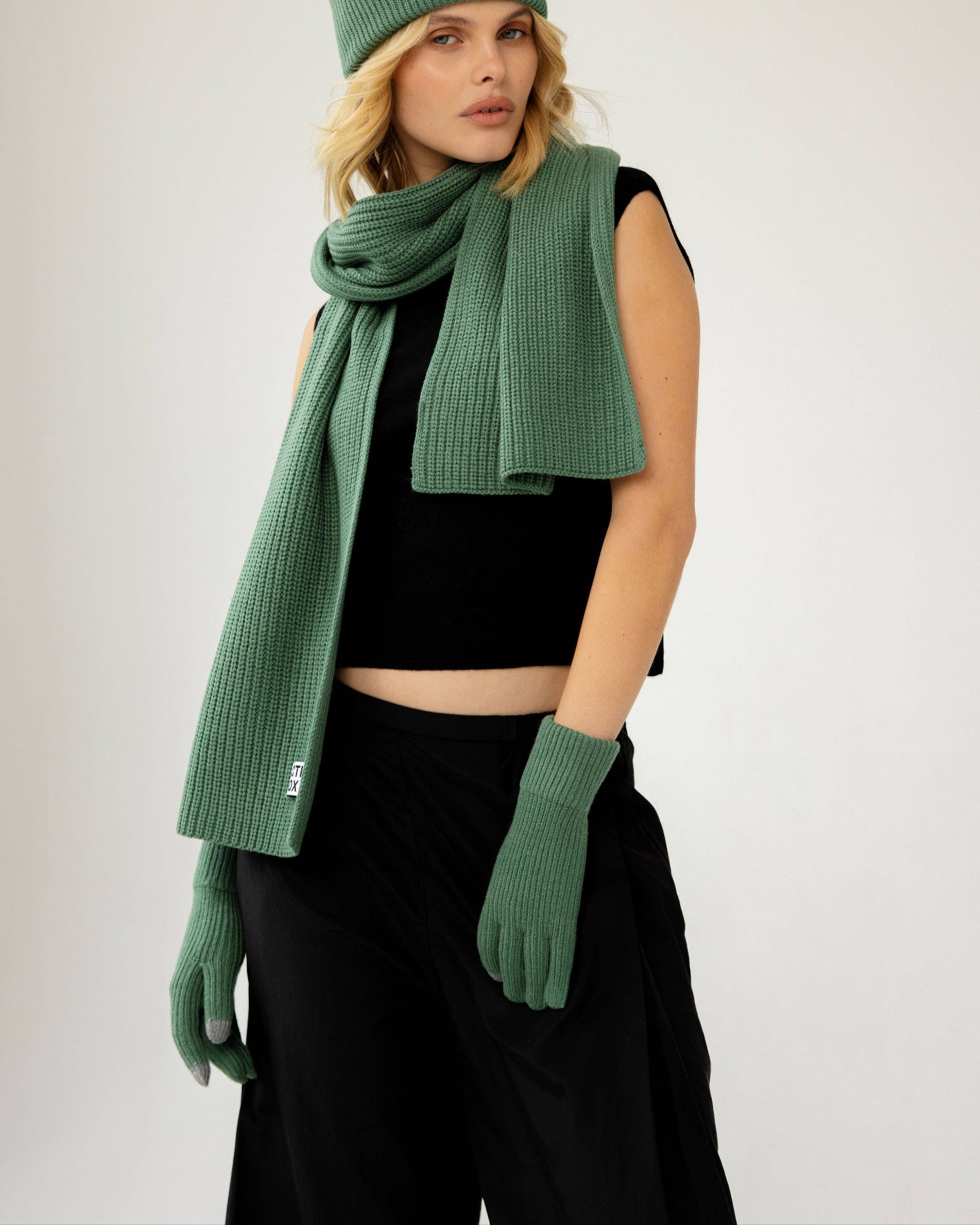 Woman wearing a green knit hat, scarf, and gloves against a white background, Green Recycled Bottle Gloves