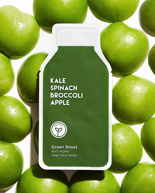 Green Reset anti-aging raw juice mask packaging surrounded by green apples on a white background