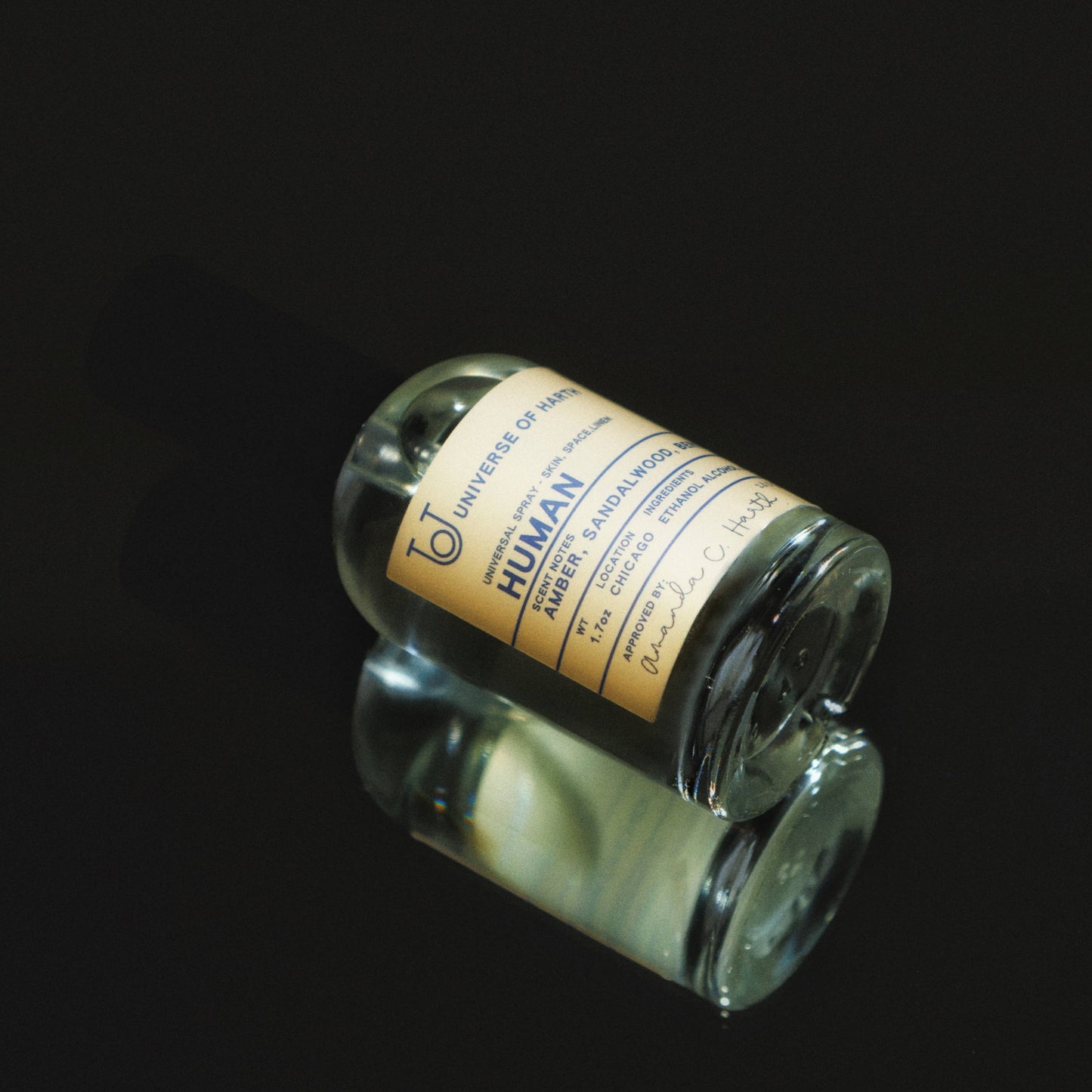 Small glass bottle with a yellow label on a black background, Human: Room, Space and Body Spray