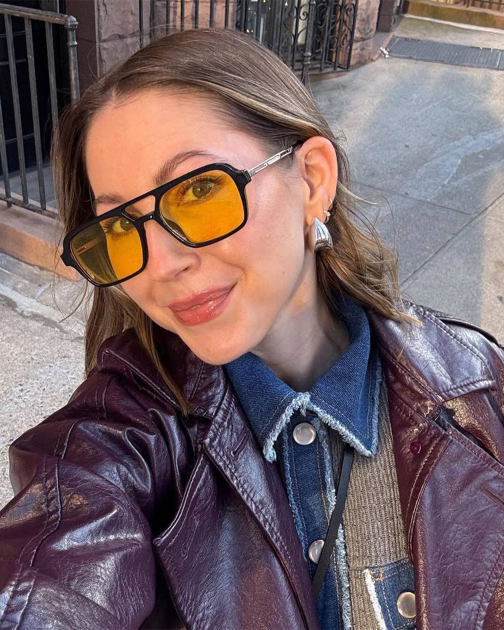 Person wearing sunglasses and a leather jacket on a city street