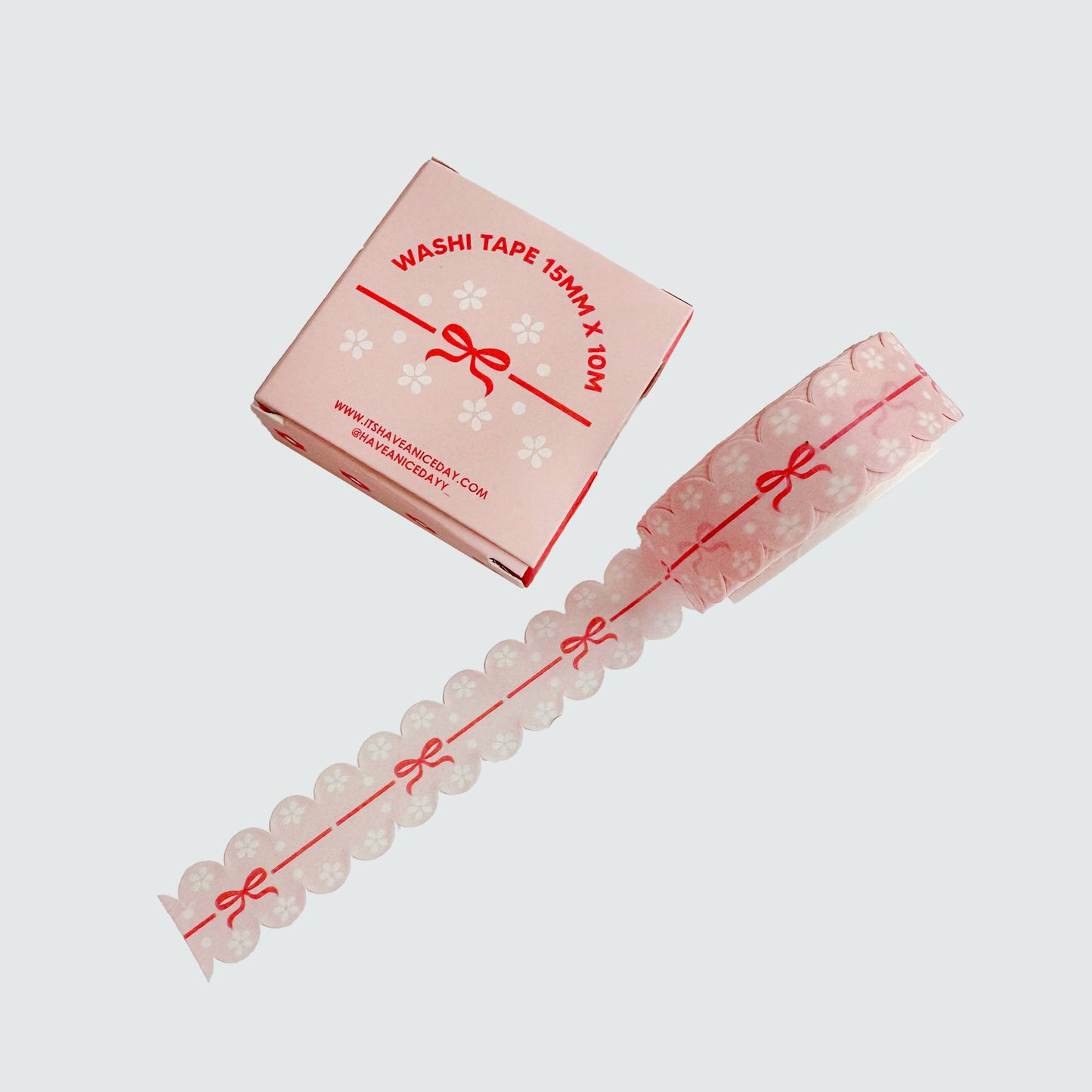 Pink washi tape with decorative bow design and packaging on a light gray background