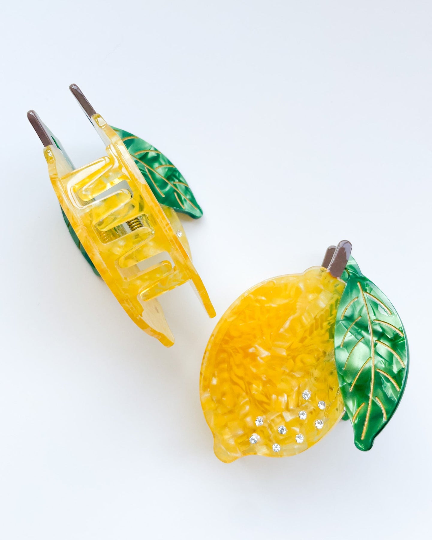 Yellow lemon-shaped hair clips with green leaves on a white background