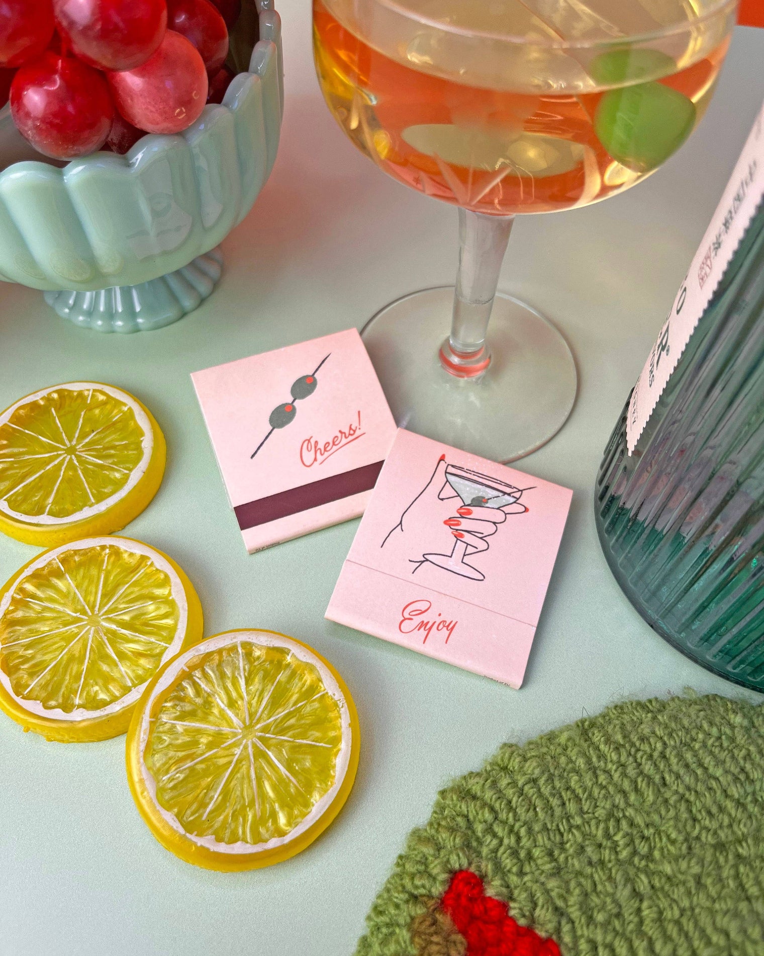 Table setting with a cocktail, lemon slices, and coasters with drink illustrations. Martini Matches