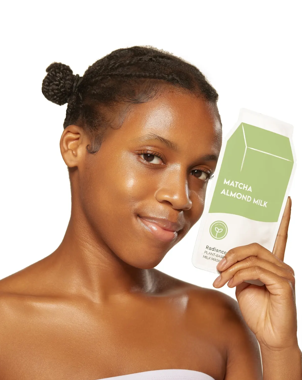 Woman holding a matcha almond milk package against a white background, Matcha Almond Milk Radiance Sheet Mask