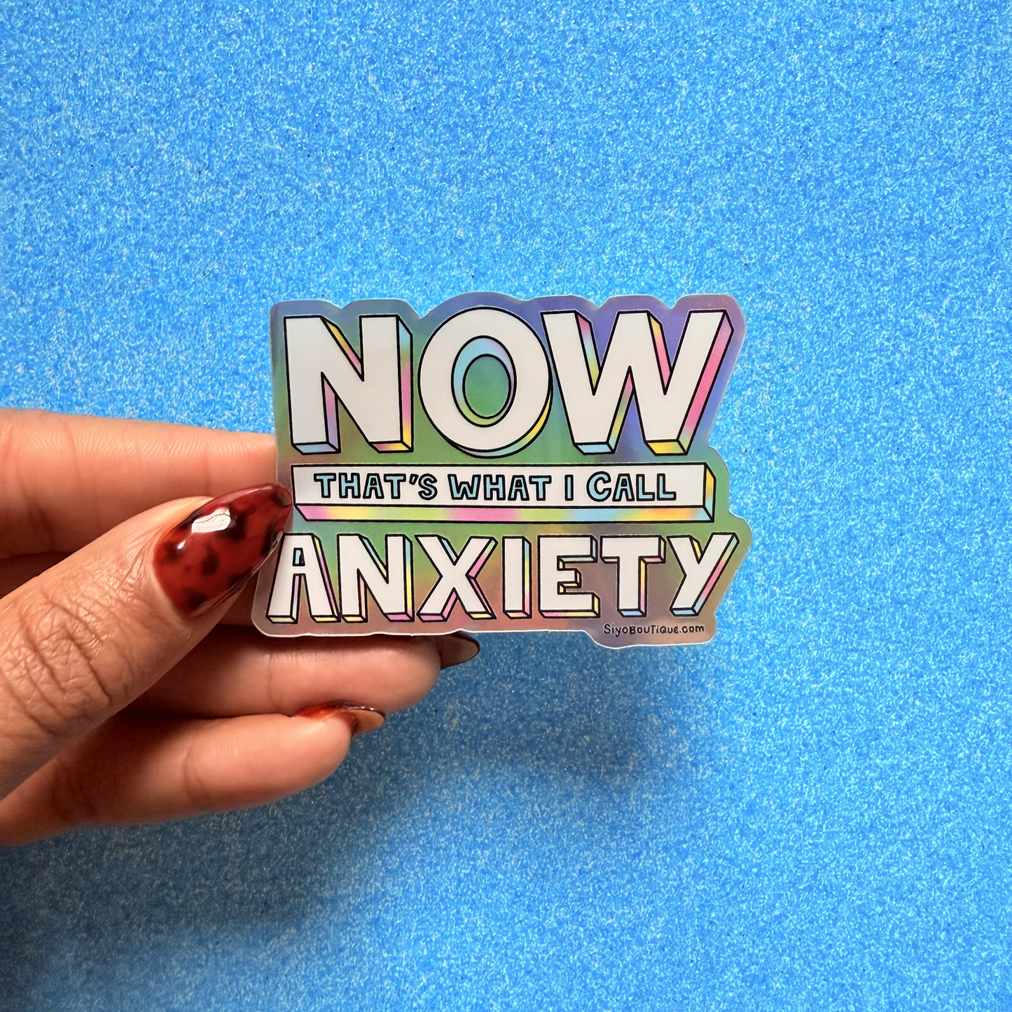 Hand holding a colorful sticker with text against a blue background