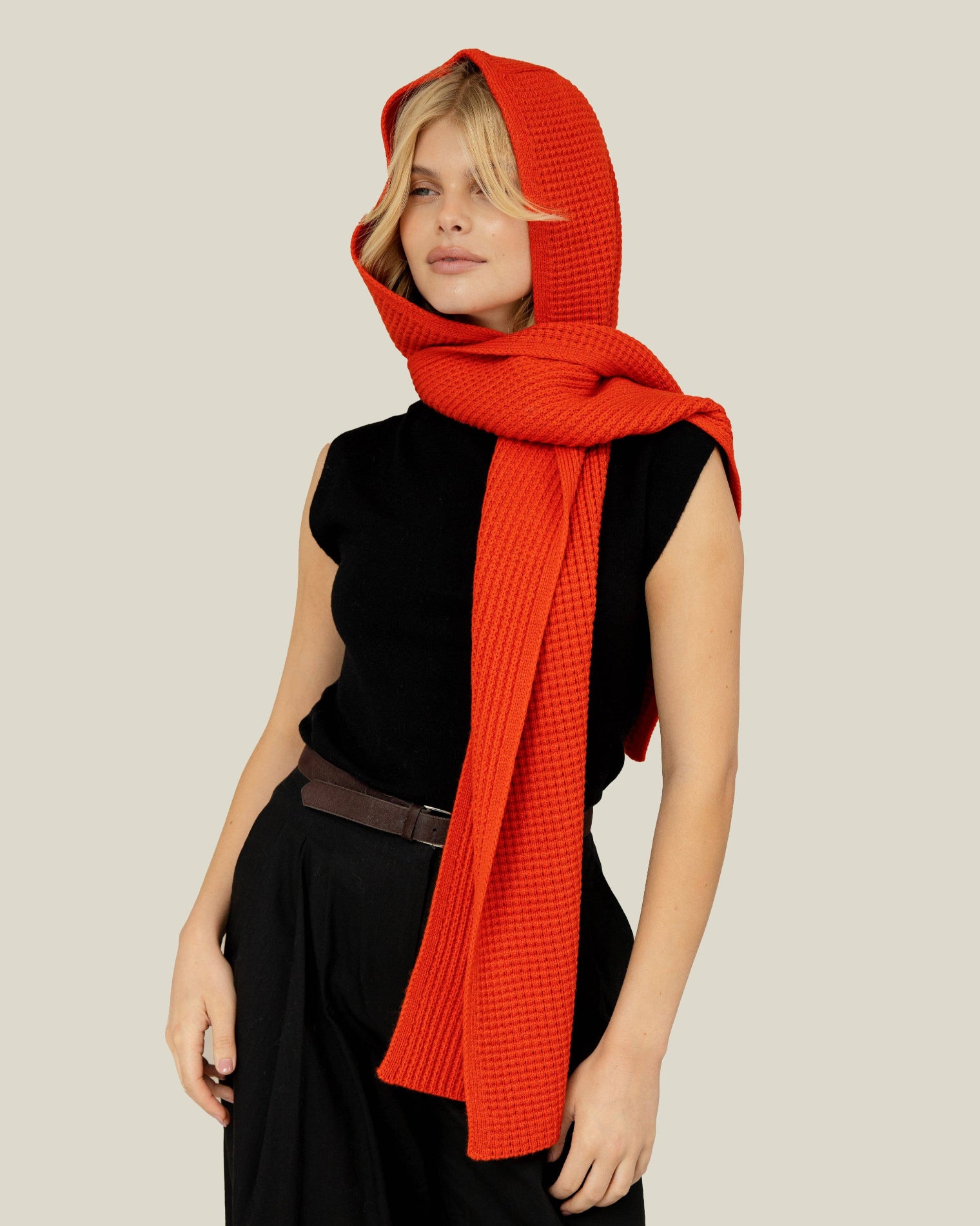 Woman wearing a bright orange scarf with a hood over her head on a beige background, Orange Recycled Bottle Hooded Scarf