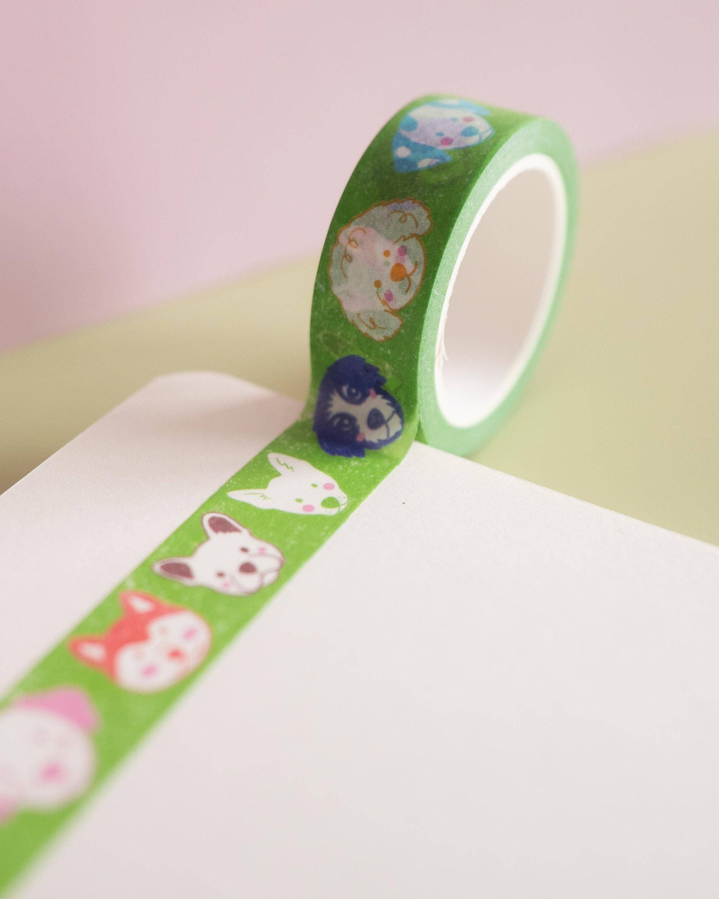 Green washi tape with animal designs on a pink and green background