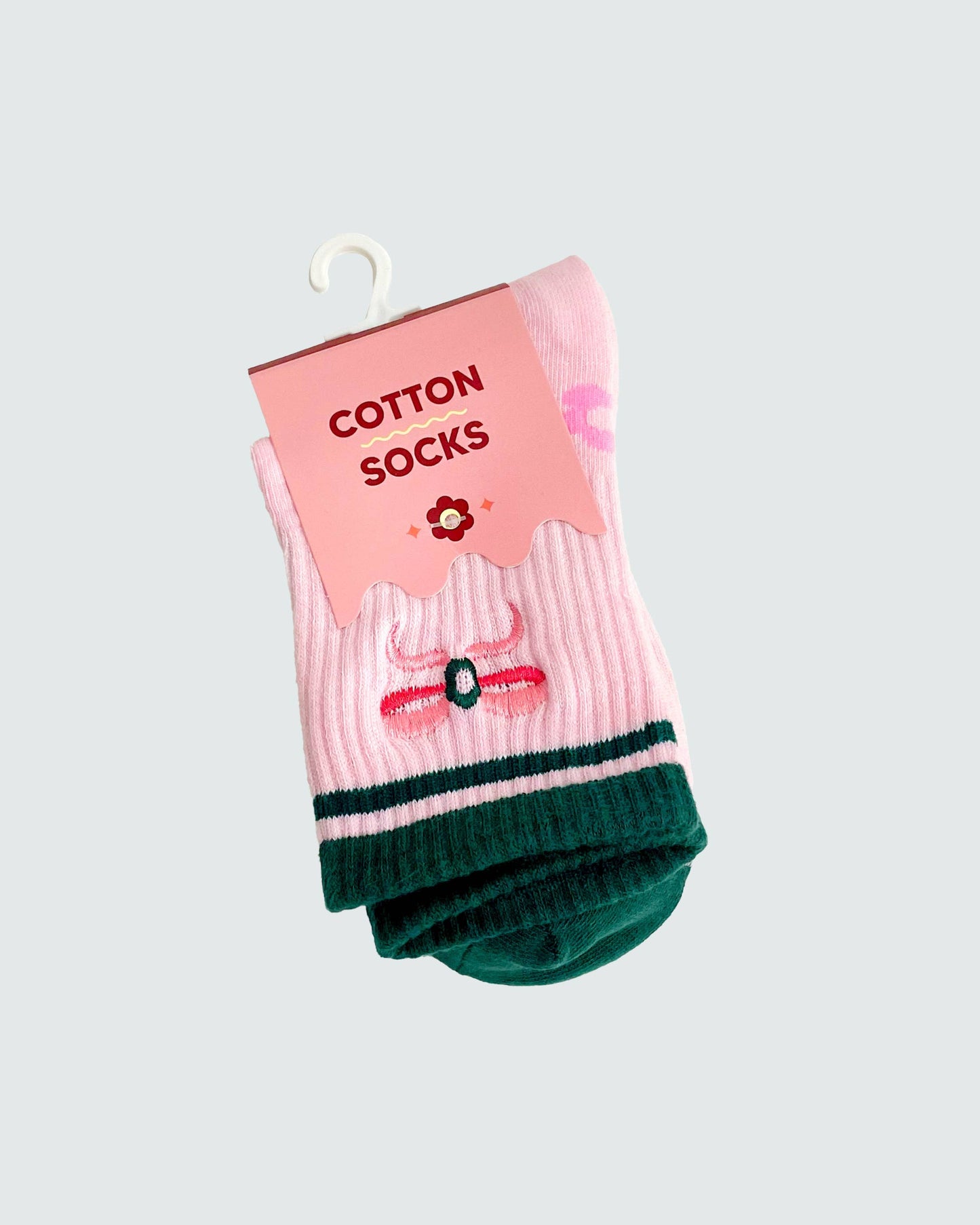 Pack of pink and green socks with a label on a light gray background