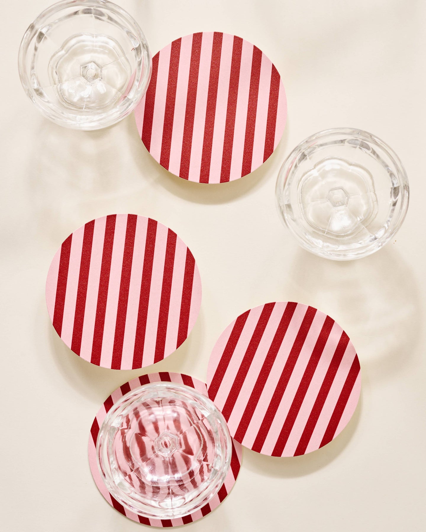 Red and white striped coasters with clear glass bowls on a beige surface