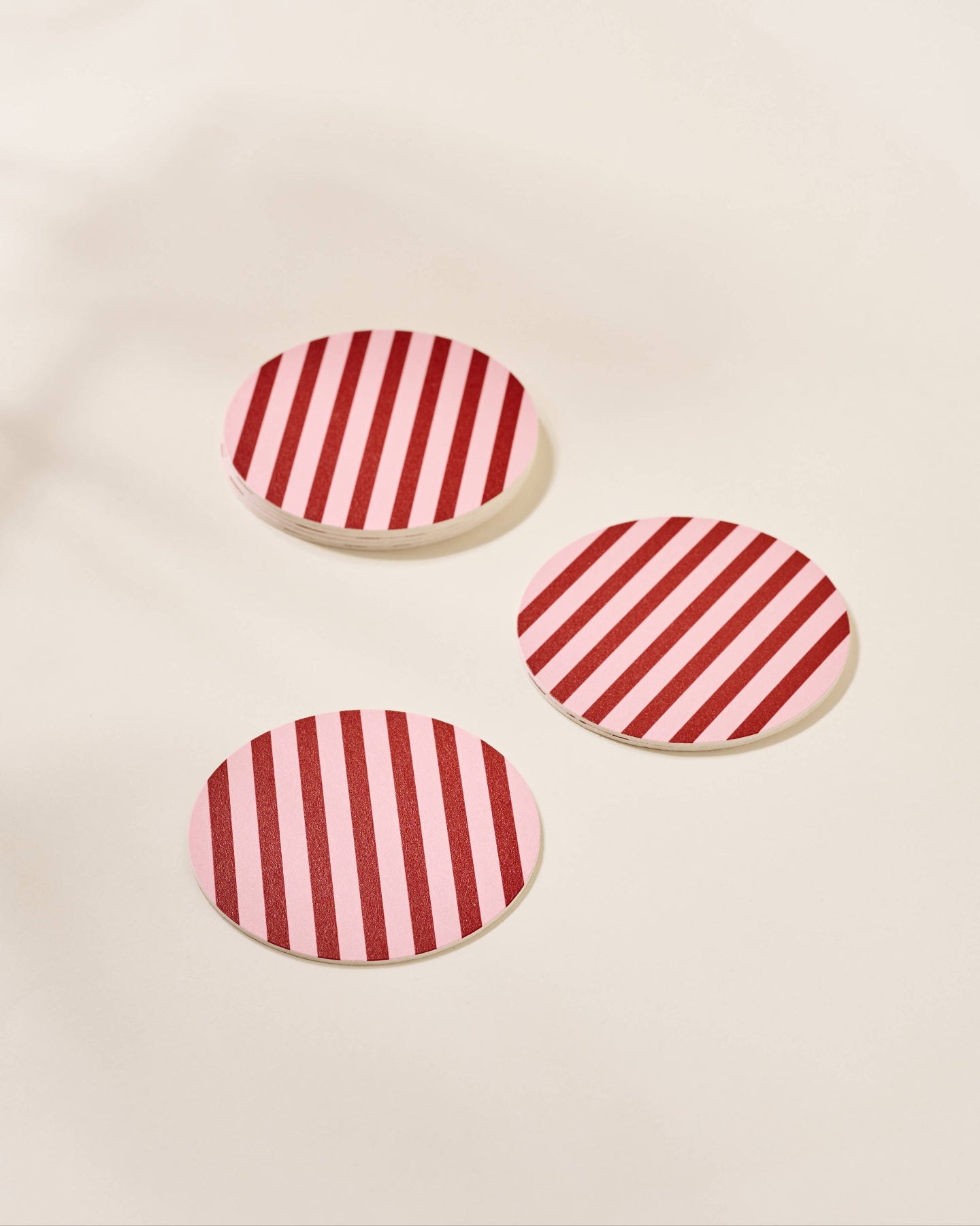 Three red and white striped coasters on a beige background