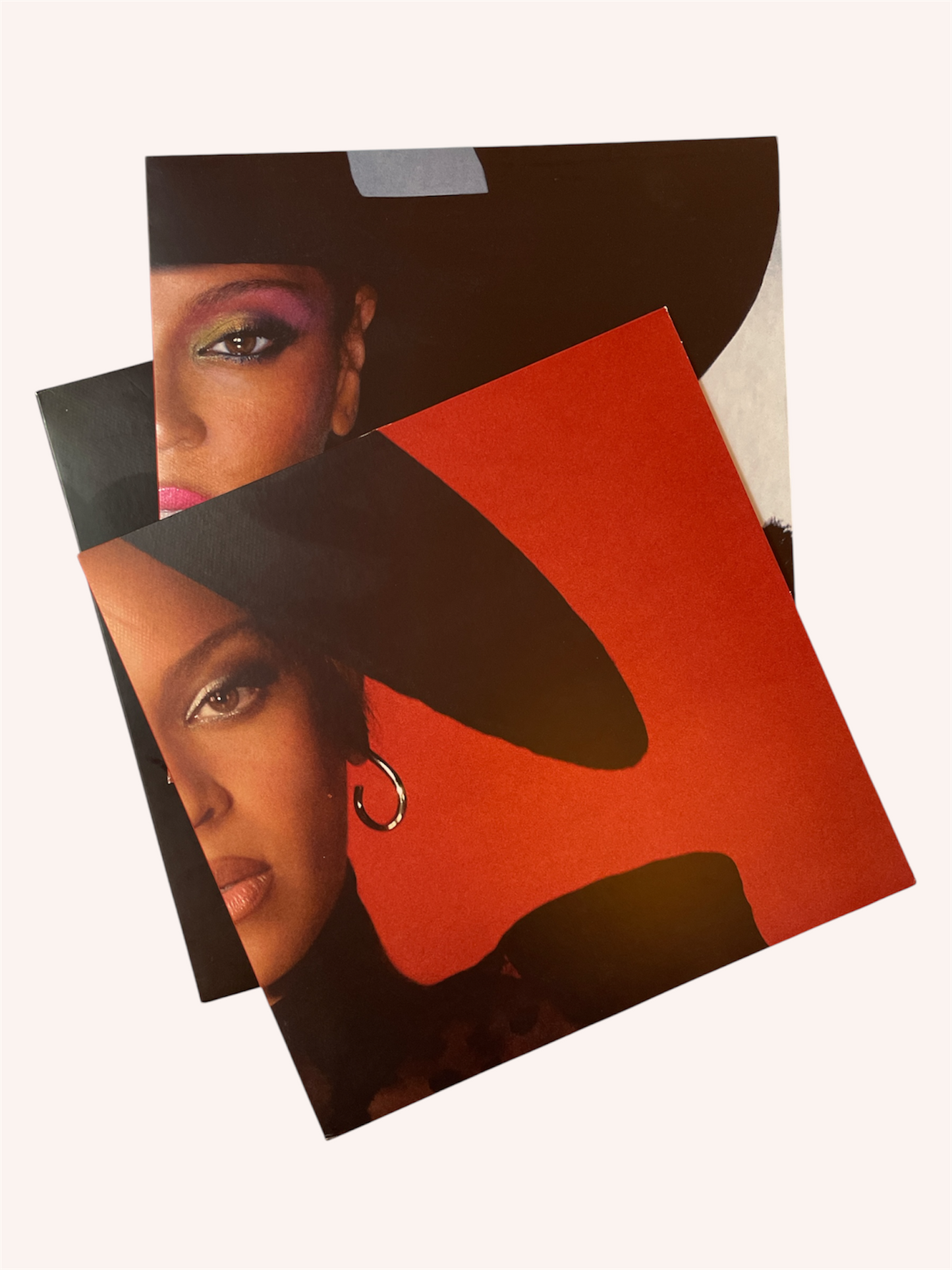 Two vinyl covers featuring a woman's face with a black hat and red, background. Renaissance Vinyl Record - Beyonce