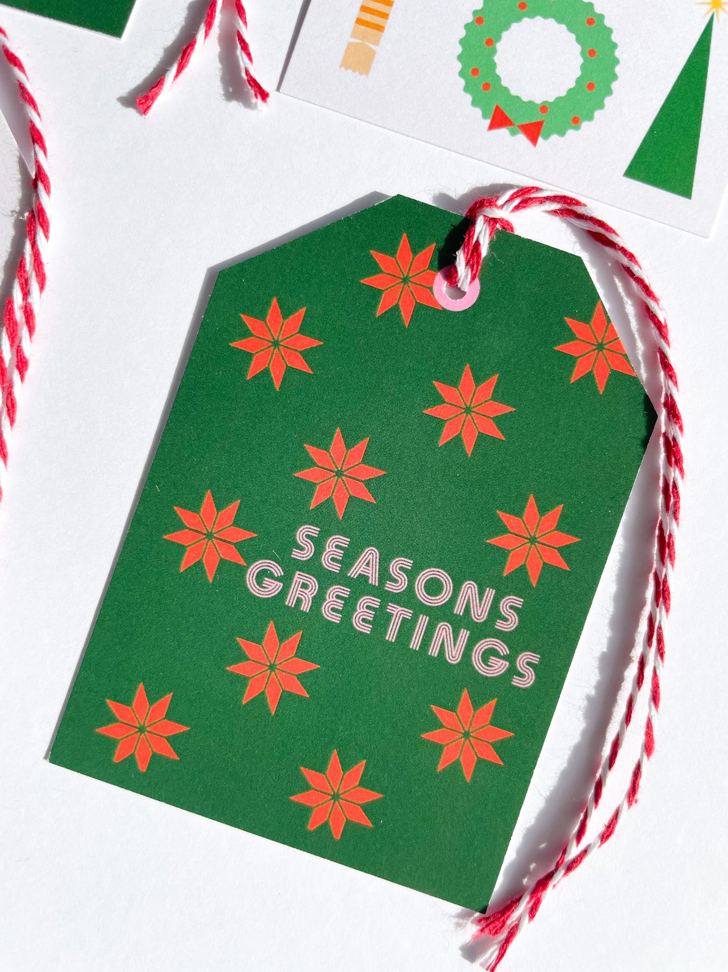 Green gift tag with red poinsettias and 'Seasons Greetings' text, tied with red and white string. Seasons Greetings Gift Tag Set of 6