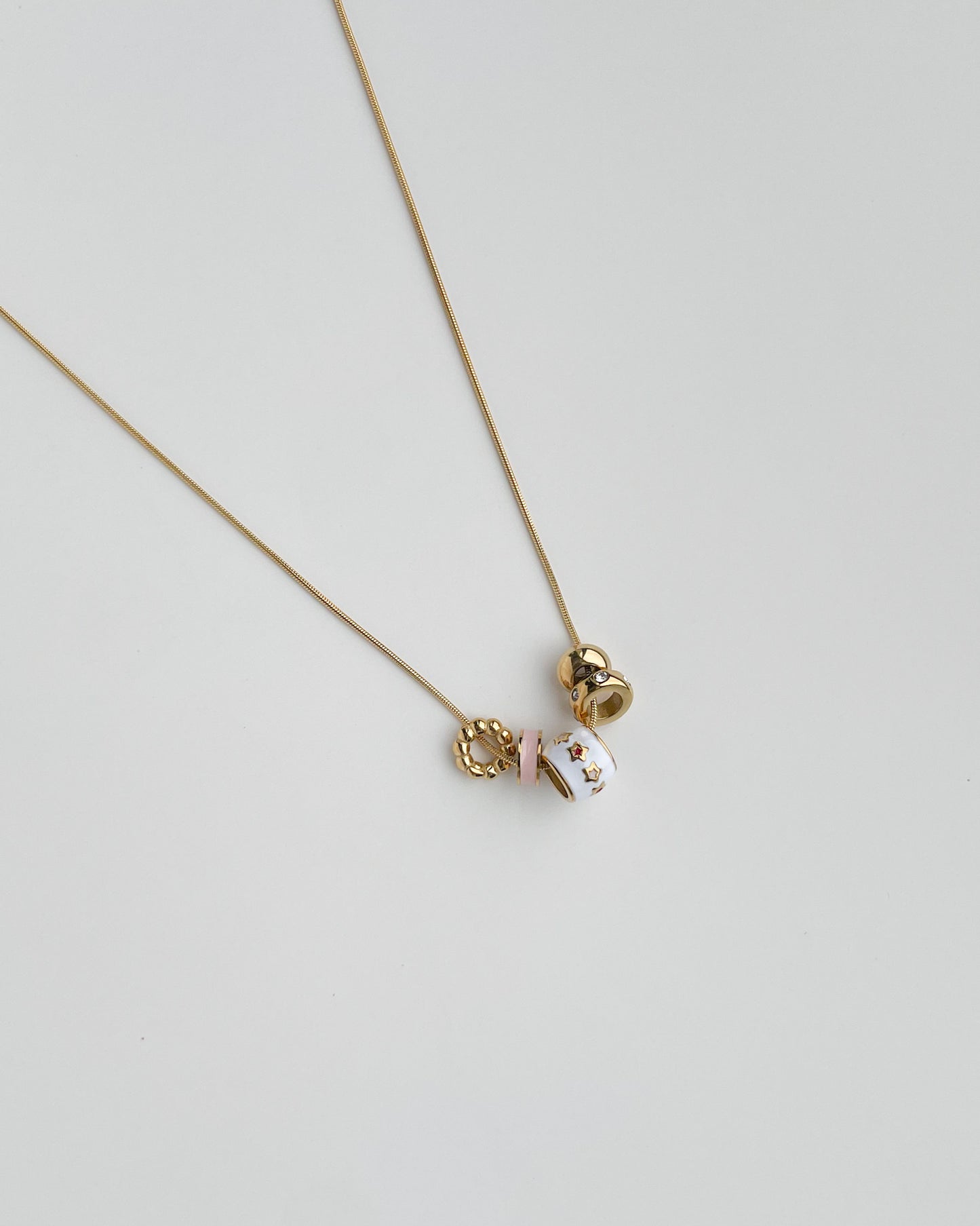 Necklace with a small pendants on a light gray background. Starry Baubles Necklace