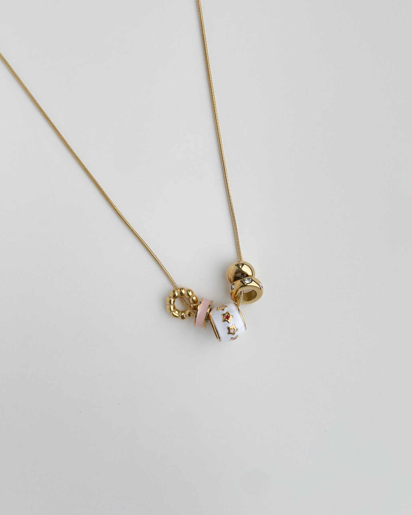 Gold necklace with three round pendants on a light gray background