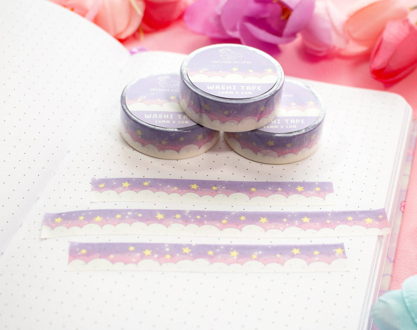 Three small round containers with lids on a notebook with decorative washi tape.