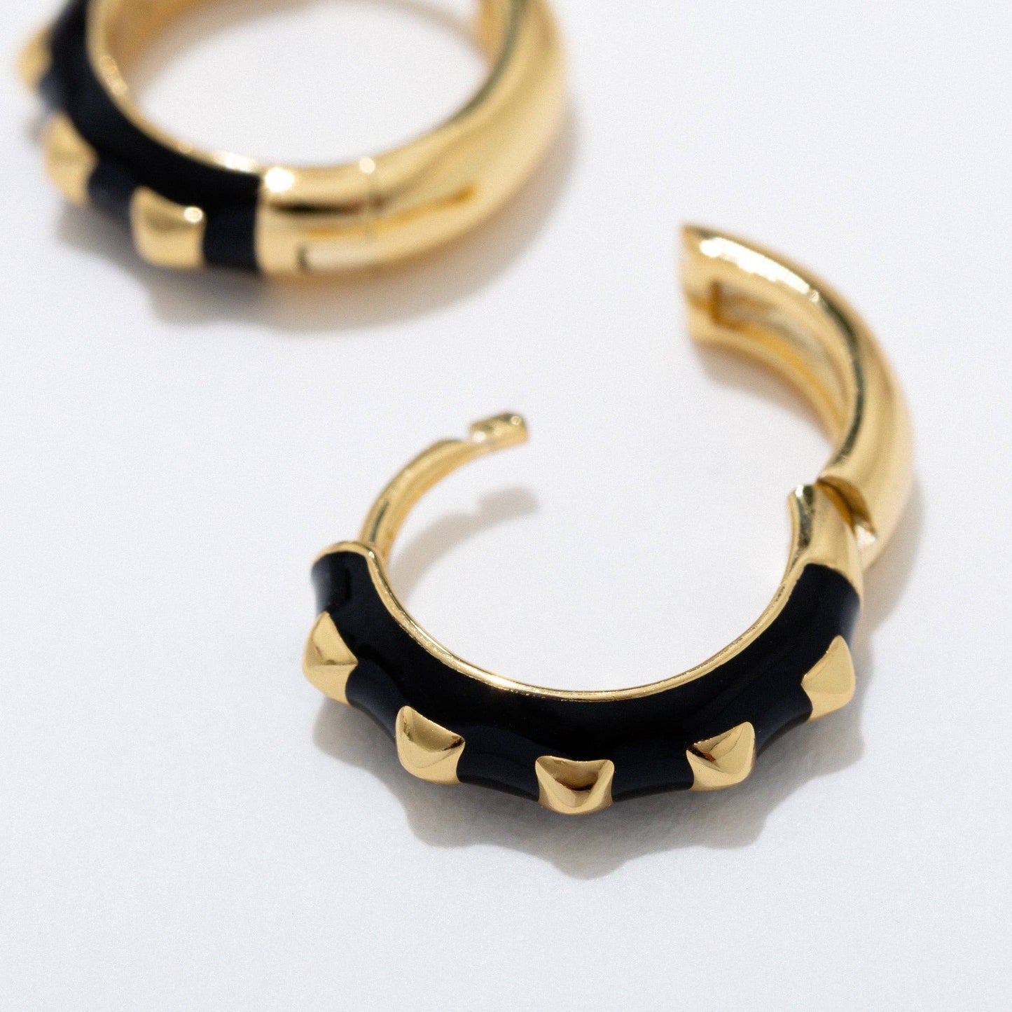 Gold hoop earrings with black accents on a white background