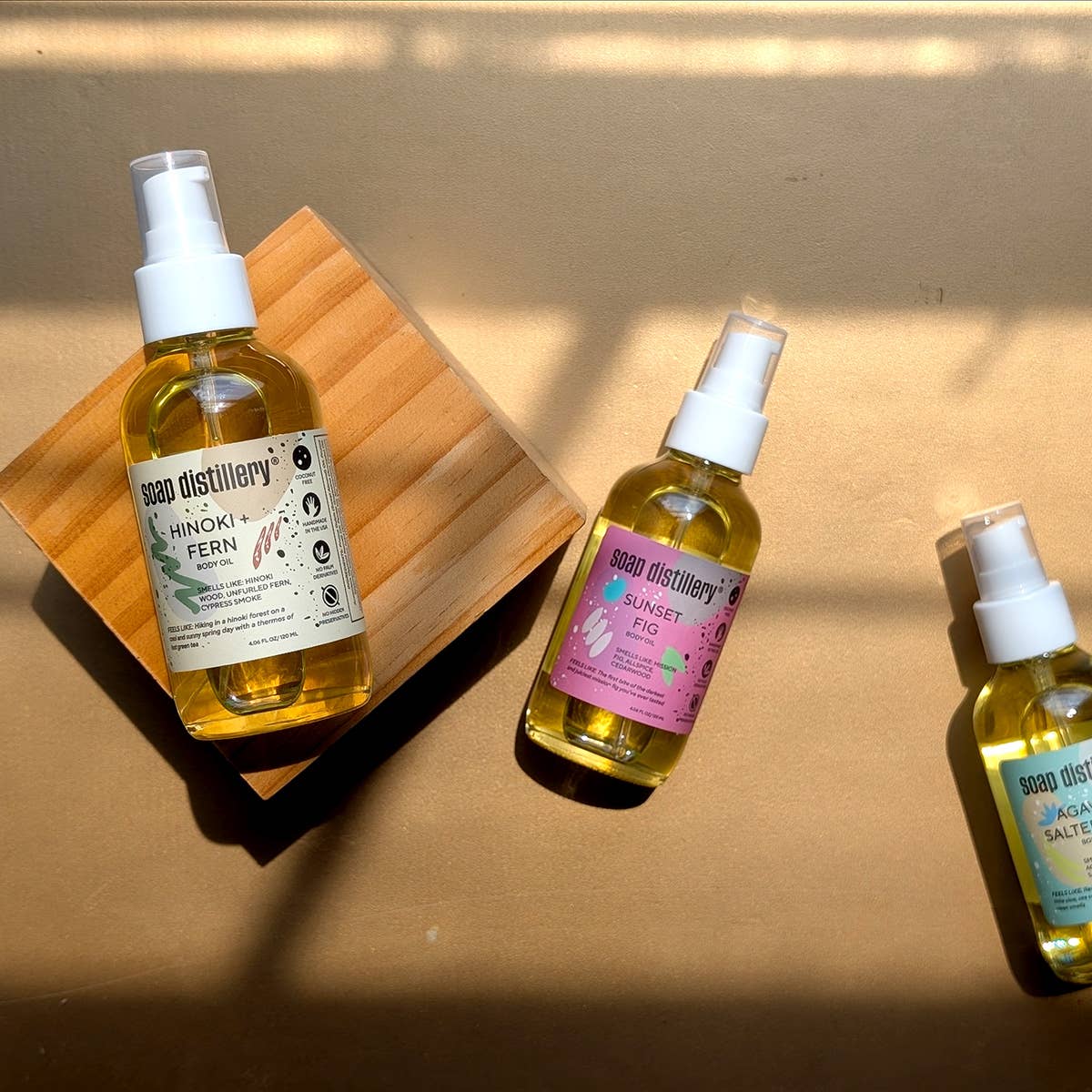 Three bottles of soap distillery products on a wooden block with a neutral background