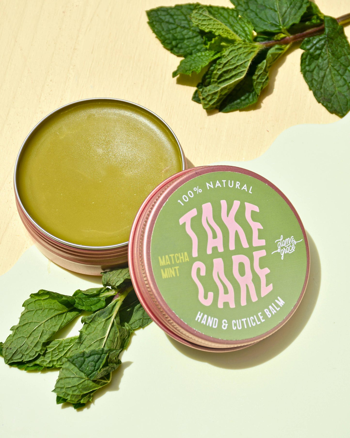 Hand and cuticle balm in a 'Take Care' container with mint leaves on a light background