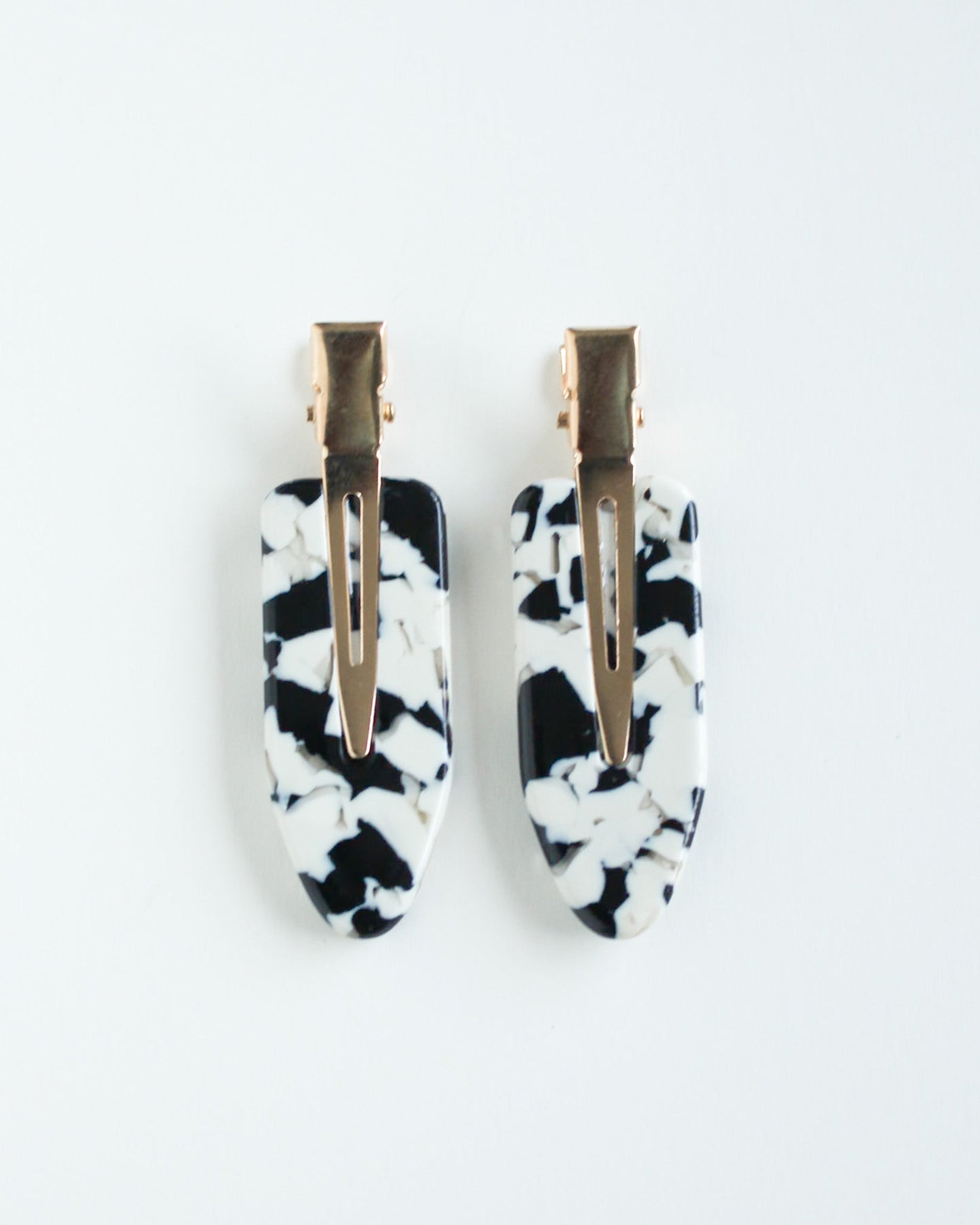 Black and white marble crease free hair clips with gold centers on a white background