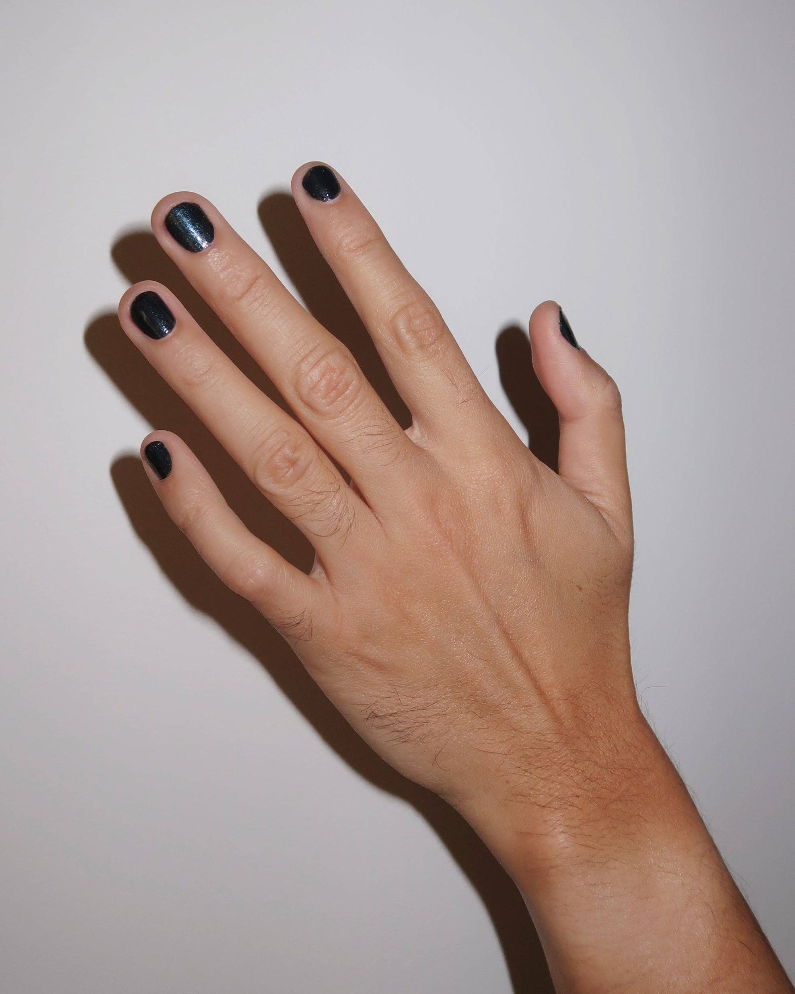 Hand with black nail polish on a plain background, Twilight Metallic Grey Nail Polish Ruth Polish