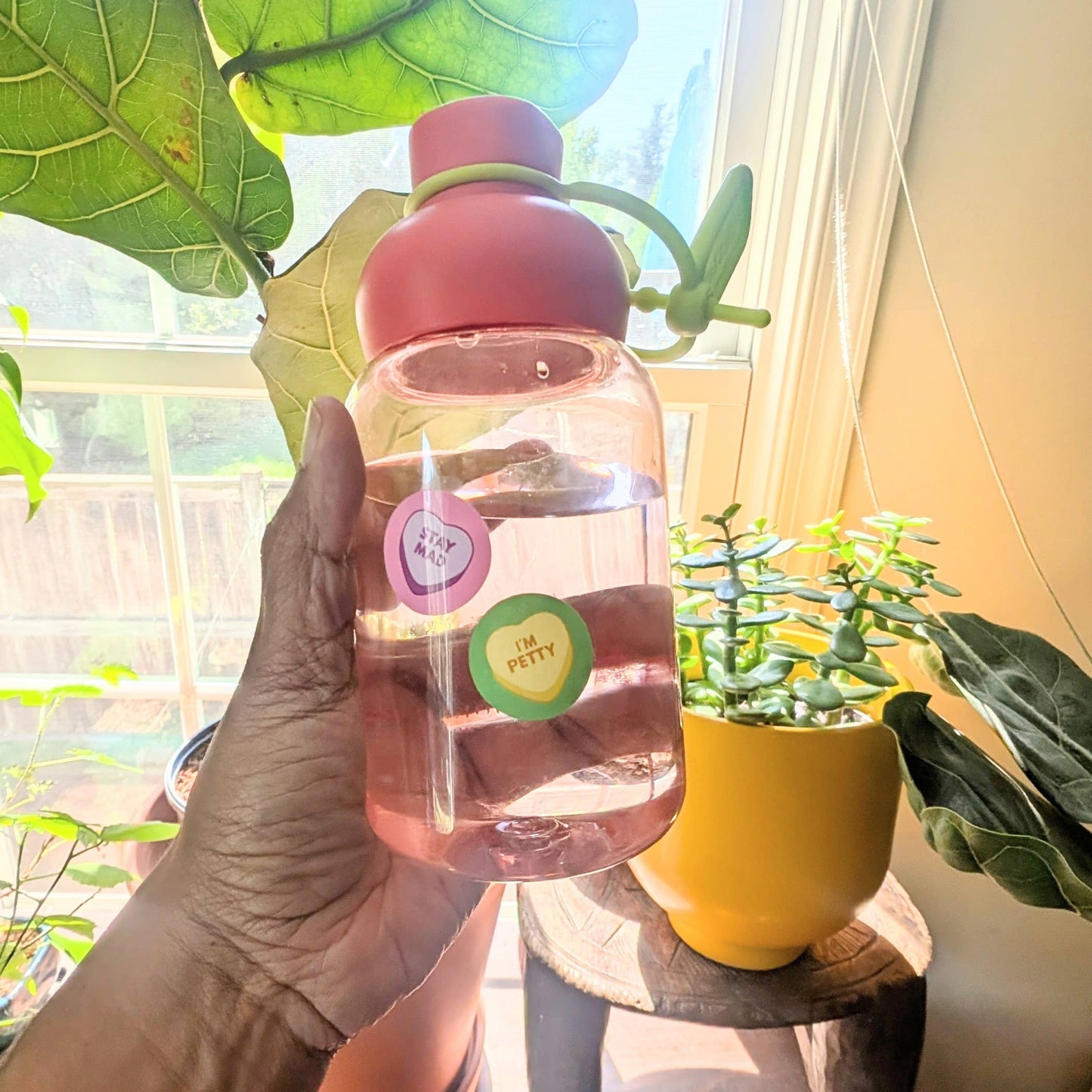Hand holding a pink water bottle with stickers in a room with plants, Unbroken Hearts Sticker Sheet