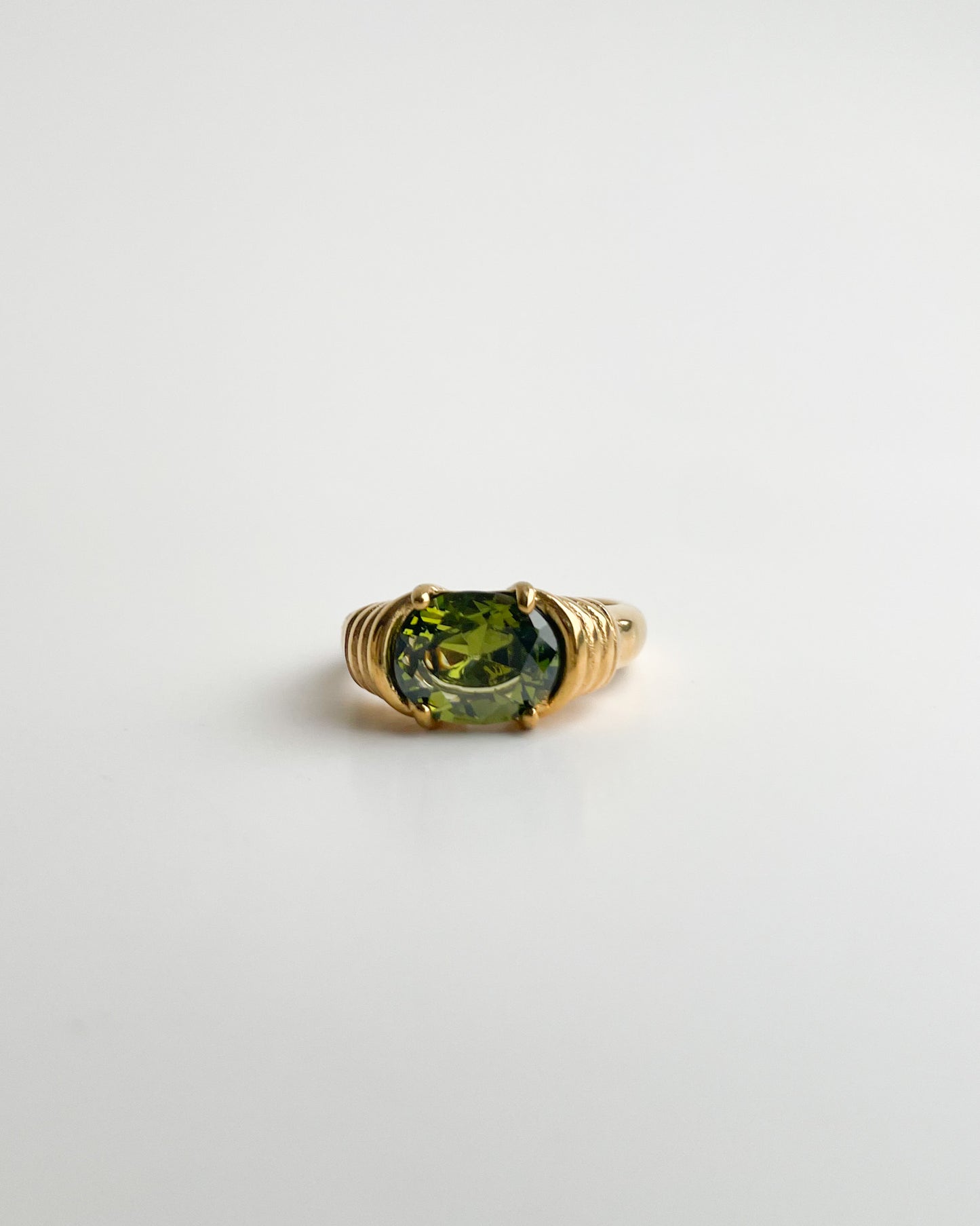 Gold ring with a green gemstone on a white background