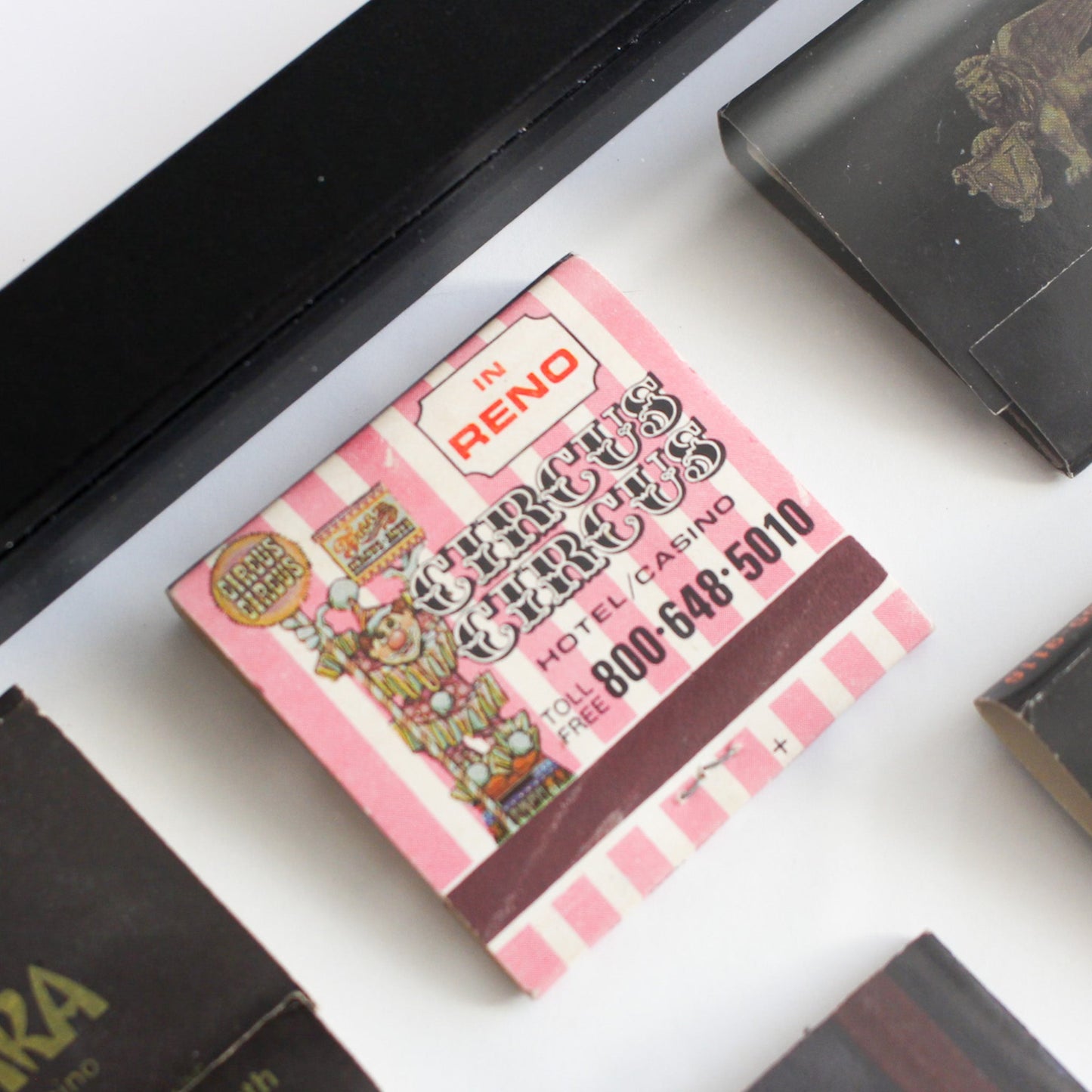 Pink and white matchbook with colorful graphics on a white surface