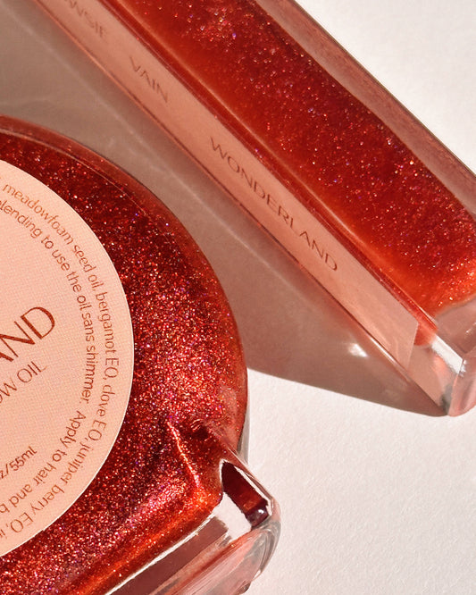 Red glittery product with 'Wonderland' branding on a white background. Wonderland Glow Oil