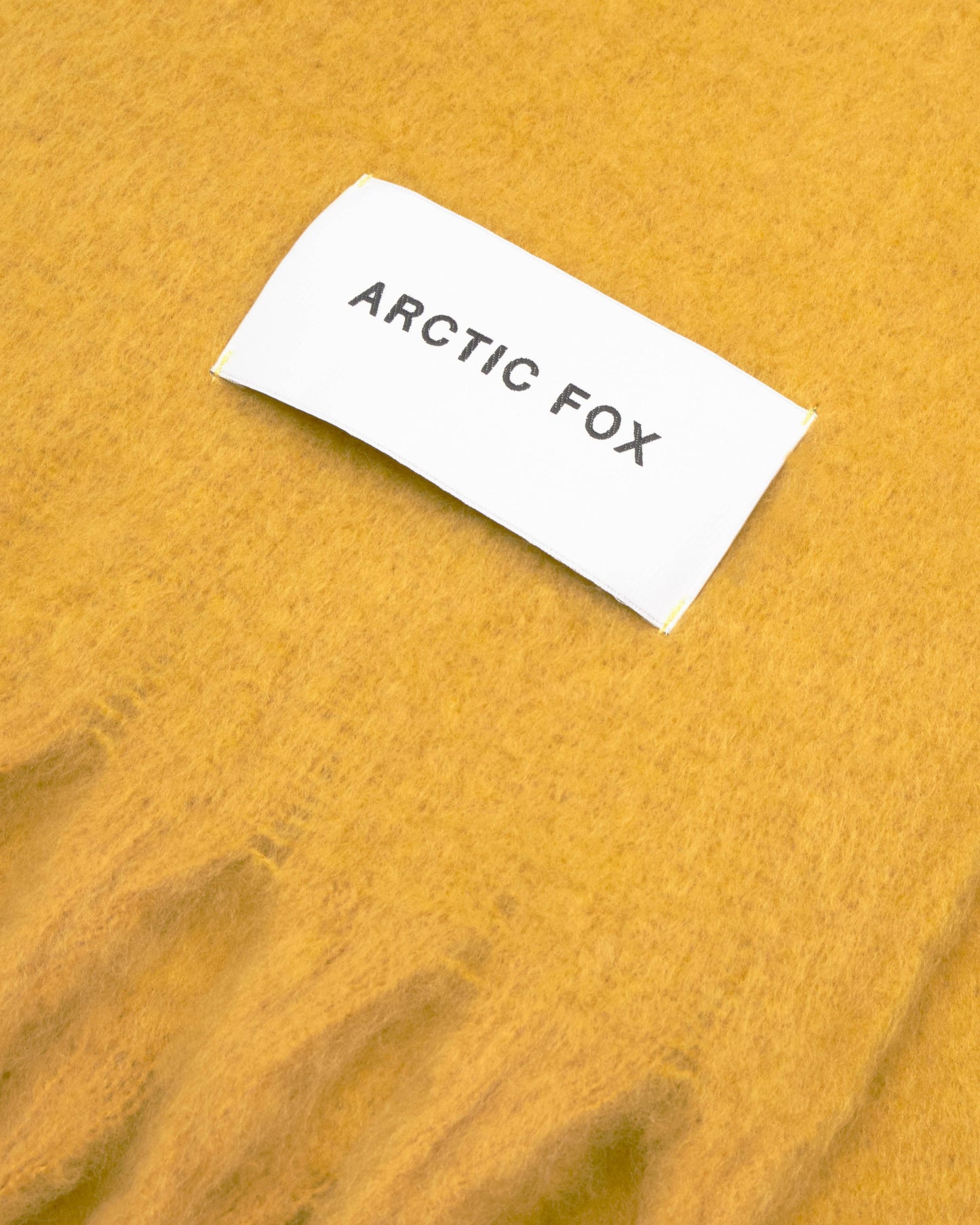 White label with 'Arctic Fox' text on a textured yellow scarf. Yellow Recycled Bottle Stockholm Scarf