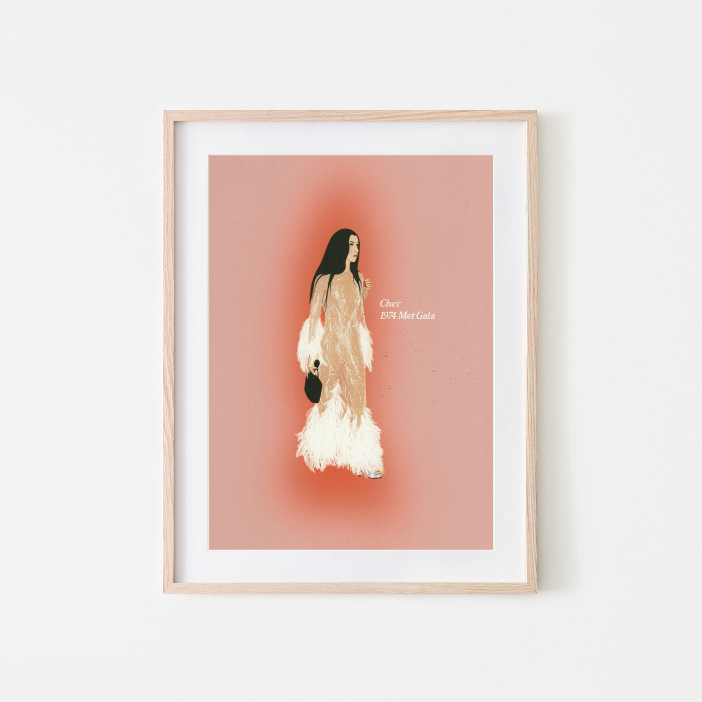 A framed fashion art print featuring a stylized illustration of a woman in a beige and white feathered dress against a dusty pink background, housed in a light wood frame with a white mat.