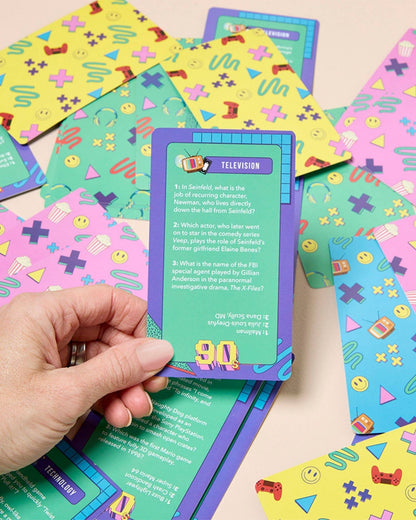Colorful card game cards with a hand holding one card on a patterned surface