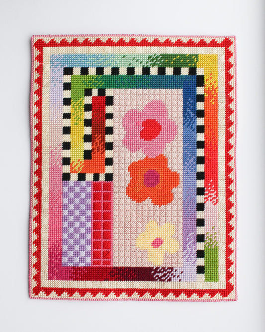 Colorful cross-stitched sampler with flowers and geometric patterns on a white background