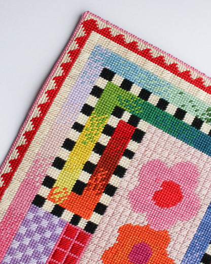Colorful quilt with geometric patterns and floral designs on a white background