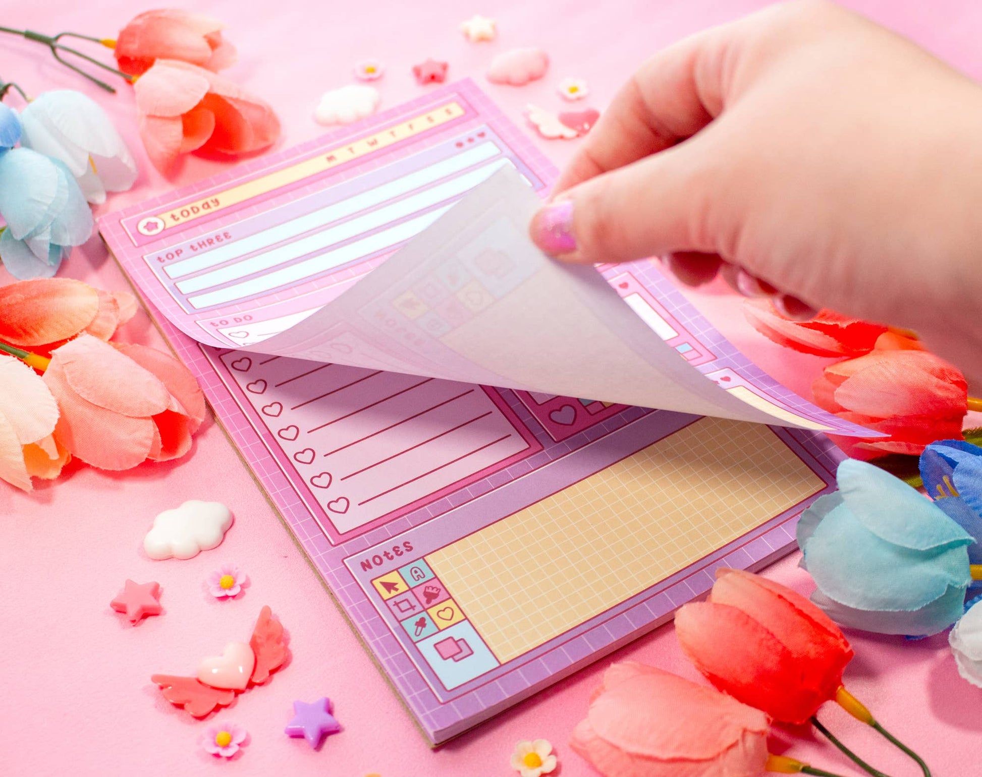 Hand holding a pink stationery set with decorative elements on a pink background