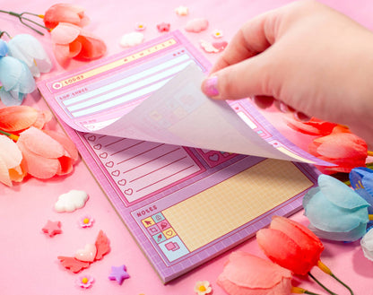 Hand holding a pink stationery set with decorative elements on a pink background