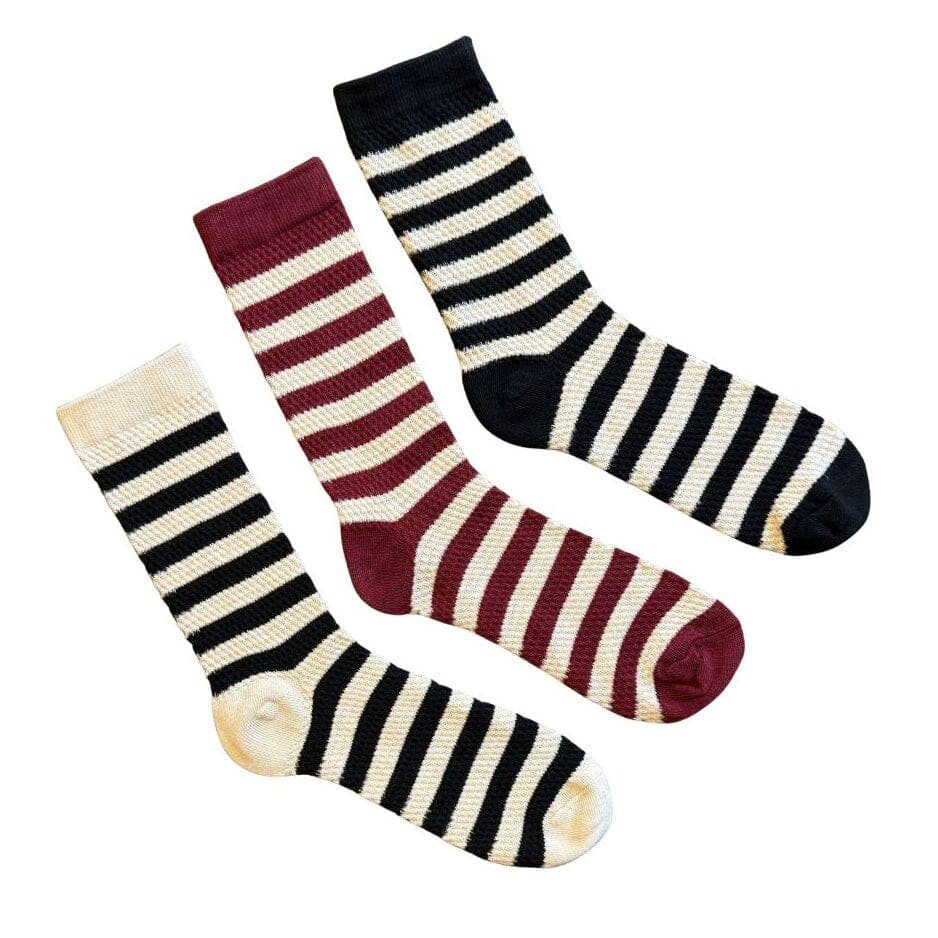 Three striped crew socks arranged diagonally on a white background: one cream and black, one cream and burgundy, and one cream and black with a burgundy toe.