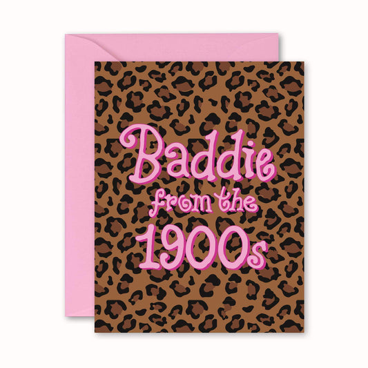 A square greeting card with a pink envelope behind it. The card has a brown leopard print background and pink text reading 'Baddie from the 1900s'.