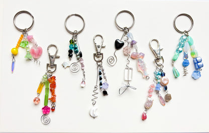 Collection of colorful keychains with beads and charms on a white background