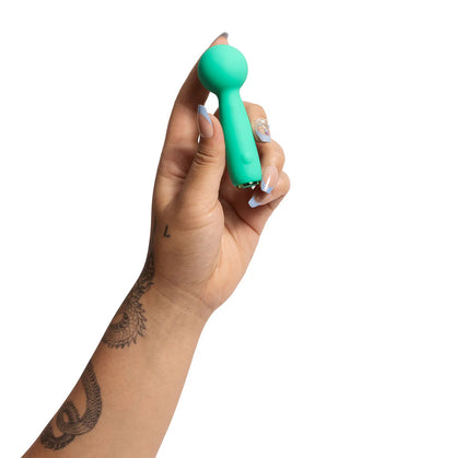 Hand holding a turquoise vibrator against a white background