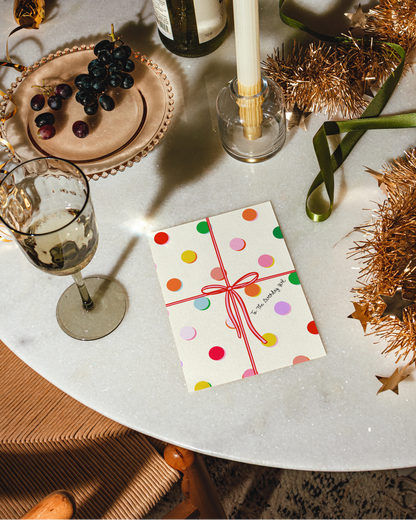 Table setting with a bottle, candle, glass, and decorative card on a marble surface.