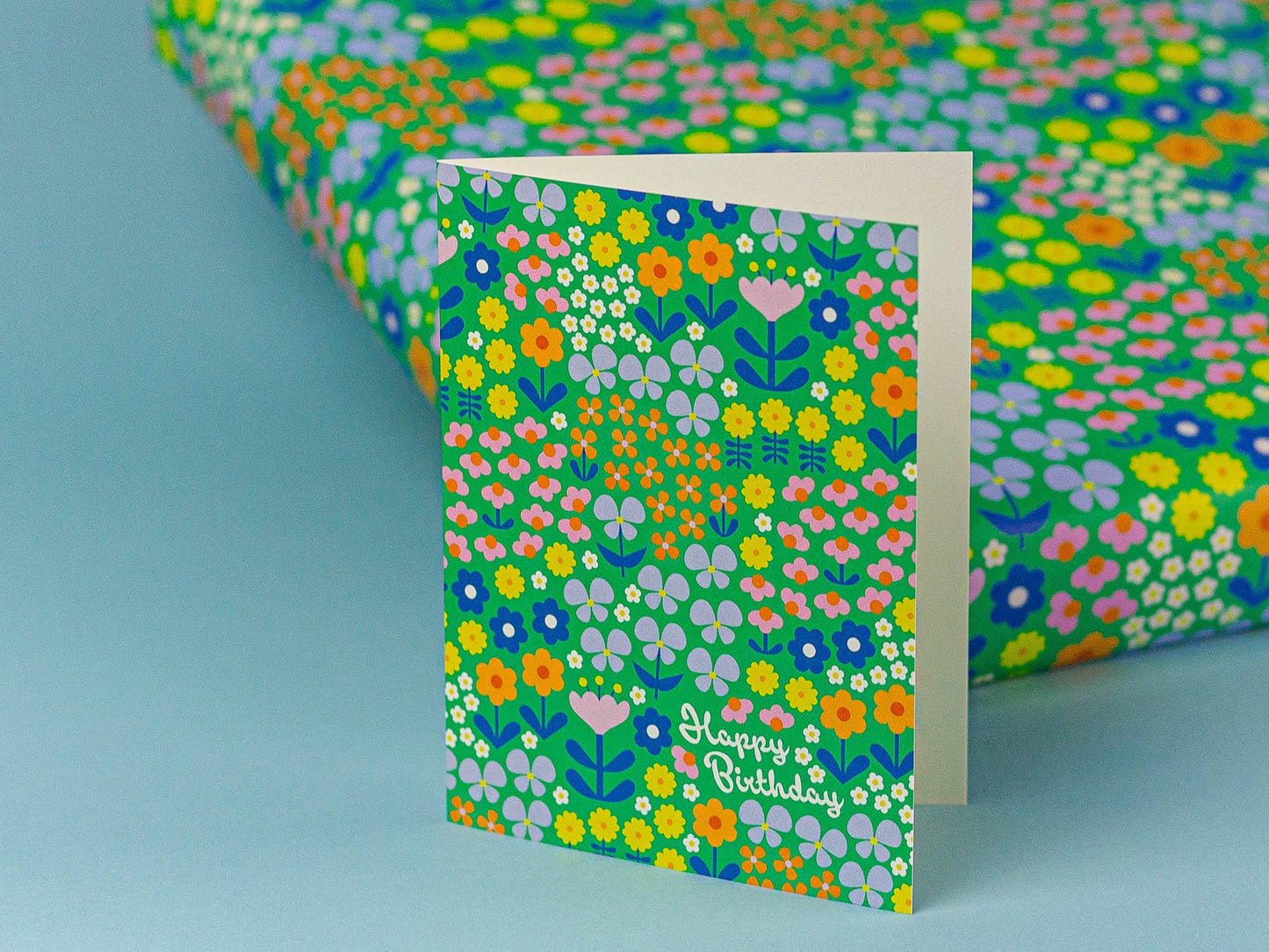 Floral patterned card with 'Happy Birthday' text on a matching wrapping paper.
