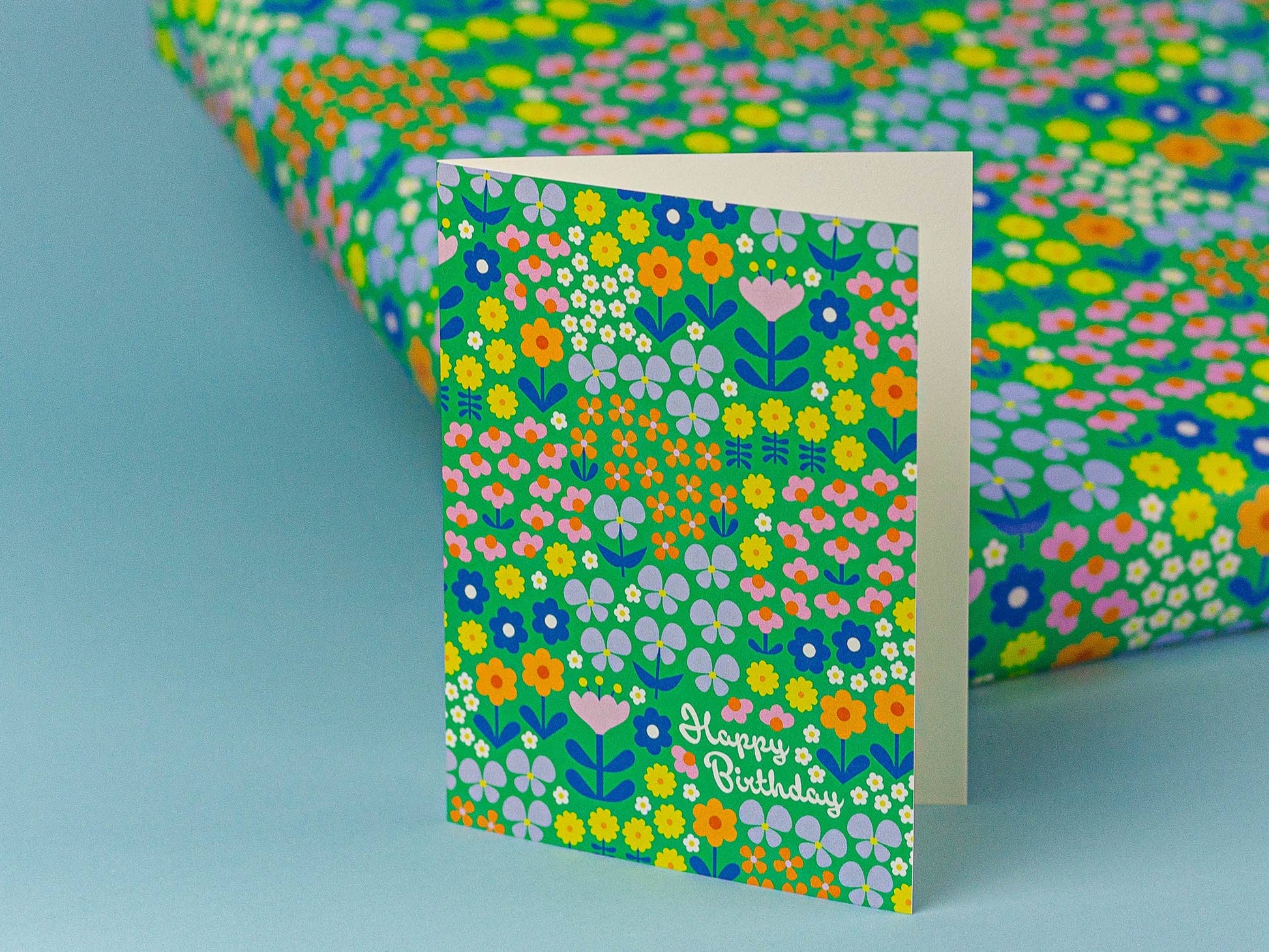 Floral patterned card with 'Happy Birthday' text on a matching wrapping paper.