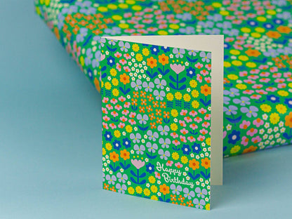 Floral patterned card with 'Happy Birthday' text on a matching wrapping paper.