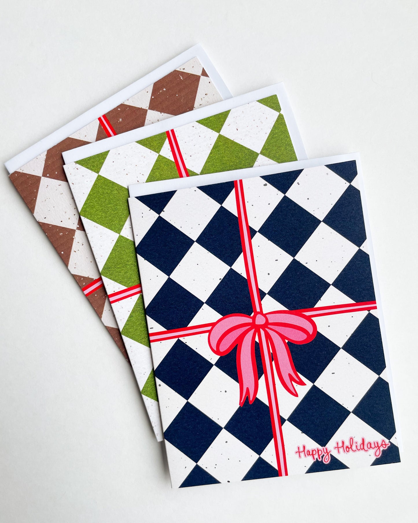 Three festive greeting cards with checkered patterns and red ribbons on a white background.